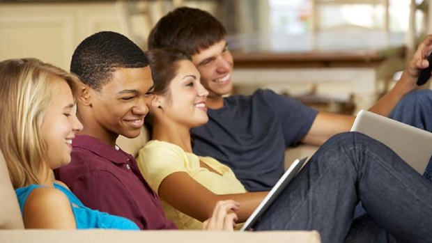 Four Teenagers  Sitting On Sofa At Home Using Tablet Computer And Laptop Whilst Watching TVFour Teenagers Sitting On Sofa At Home Vetta iStock Photo File #20287259