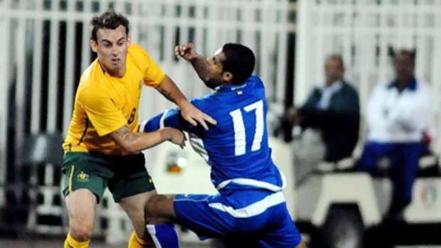 Socceroos midfielder Luke Wilkshire looks to break clear of his Kuwaiti opponent.