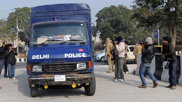 Police drive the vehicle believed to be carrying the accused in a gangrape and murder case.