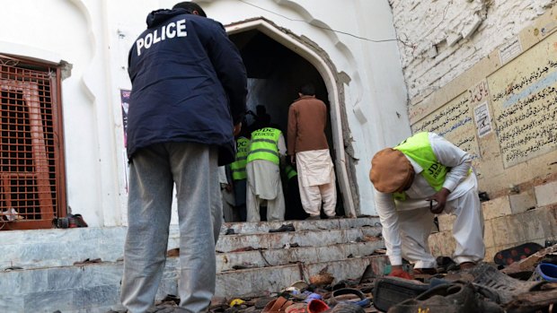 Pakistani police gather evidence following the bomb attack on a Shiite mosque.