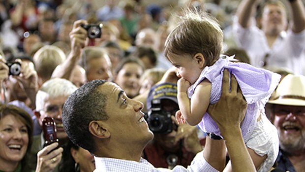 Barack Obama lifts 11-month-old Katirie Duran during a town hall meeting in Montana to sell his health-care reform package, which has been jeopardised by the right.