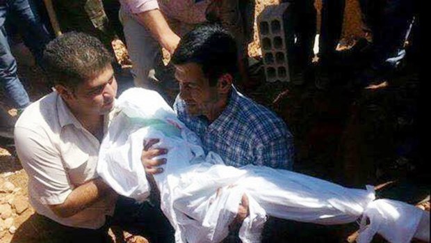 Abdullah Kurdi carries the body of one of his sons during their funeral in Kobane, Syria, last year.