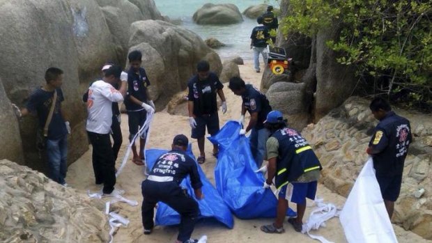 Thai officers work near the bodies of two British tourists found murdered on a Thai beach.