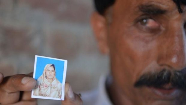 Pakistani Mohammad Iqbal   holds up an image of his wife Farzana Parveen, who was allegedly beaten to death with bricks by her father and other family members for marrying a man of her own choice, in Chak 367.