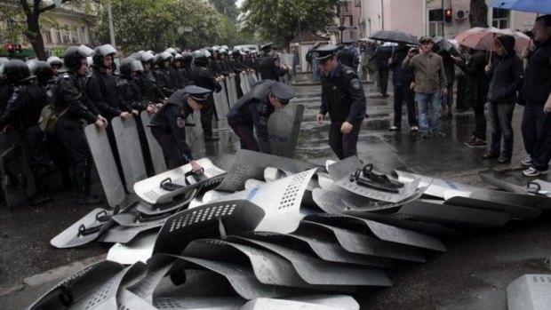 Ukrainian police work to remove riot shields left on the ground by their colleagues outside police headquarters in Odessa. Interim prime minister Arseniy Yatsenyuk had blamed police corruption for the failure to quell unrest in the city.