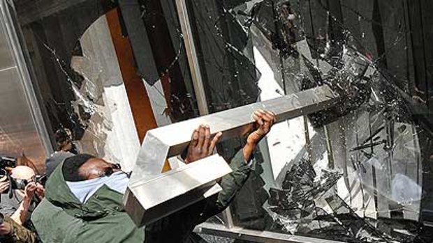 A protester throws a metal object through the window of a Royal Bank Of Scotland branch as the G-20 protests in London escalate.