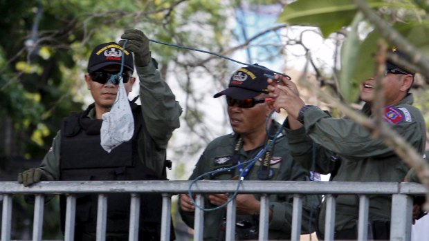 Members of the Thai explosive ordnance disposal unit recover pieces of evidence.