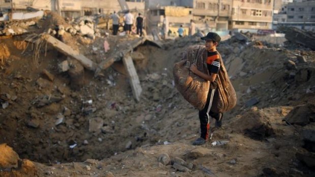 A Palestinian boy carries his belongings past what Gaza police said was the site of his family's Gaza City house destroyed in an Israeli air strike on Wednesday.
