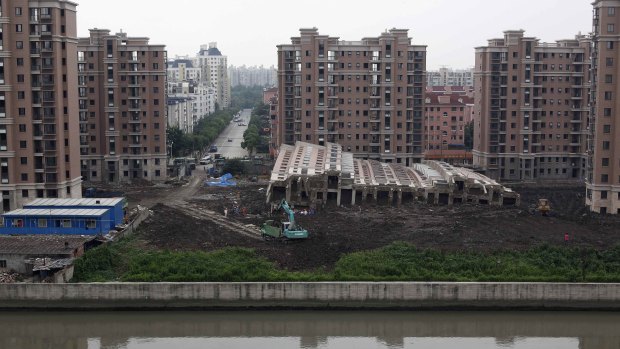 A 13-storey apartment building lies on its side after toppling and burying one worker in Shanghai on Saturday.