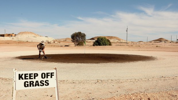 A local rakes out the green at the Coober Pedy Golf Course.