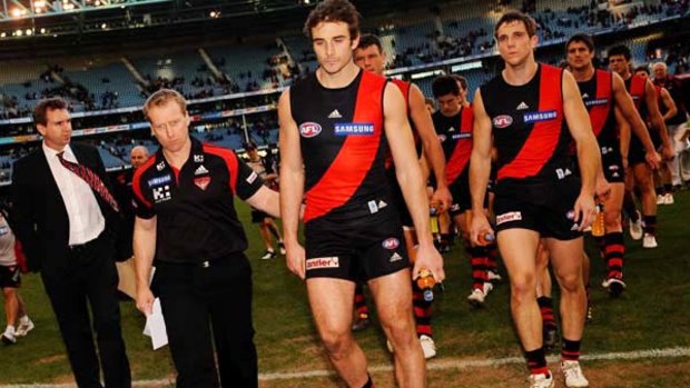 Bomber coach Matthew Knights gives skipper Jobe Watson a consoling pat as they trudge off Etihad Stadium yesterday.