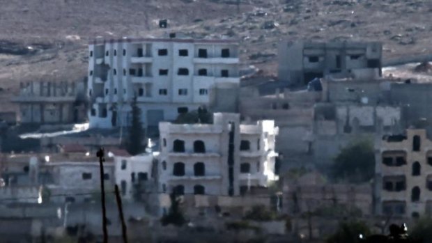 An Islamic State (IS) flag (top) flutters on the roof of a building in the Syrian town of Kobane.