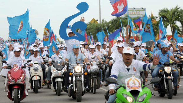 Flying the flag: Supporters of the Cambodian People's Party ride to a campaign rally.