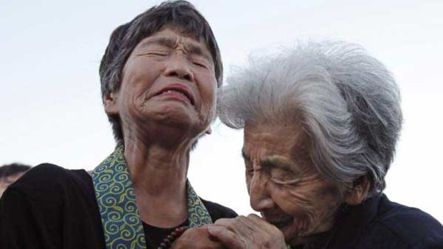 Tsuyuko Nakao, 92, and Kinuyo Ikegami, 77, both lost family in the Hiroshima bombing and console each other as they pray at the 65th anniversary. <i>Picture: AFP</i>