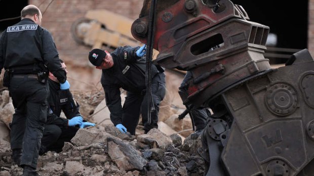 Careful now: Investigators examine a damaged excavator where a World War II bomb exploded in western Germany.