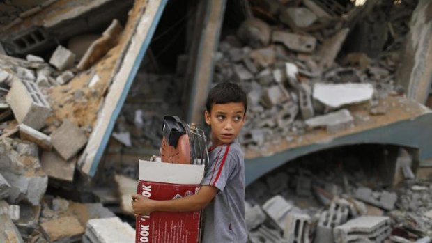 A Palestinian boy carries belongings past a destroyed house in Gaza's Shujaiya neighbourhood.