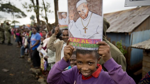 A boy holds a picture of Pope Francis as he awaits his arrival at the Kangemi slum in Nairobi.