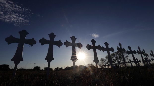 The sun sets behind 26 crosses placed in a field before a vigil for the victims of the First Baptist Church shooting in Sutherland Springs, Texas. 