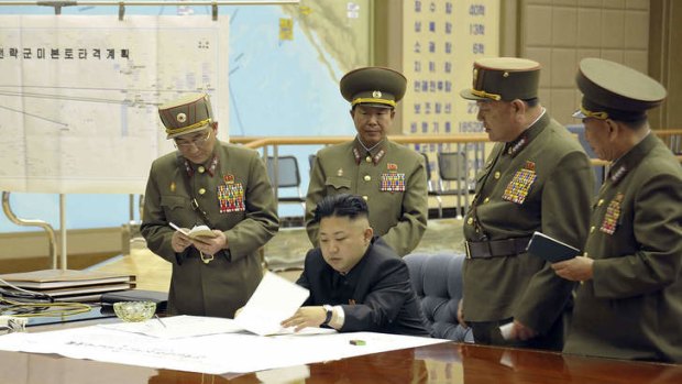 This photo taken and released by North Korea's official Korean Central News Agency (KCNA) on March 29, 2013 shows, according to KCNA, North Korean leader Kim Jong-Un discussing the strike plan with officers.  The lettering on the map, rear left, reads as "Strategic Forces' US Mainland Striking Plan"