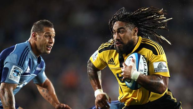 Ma'a Nonu of the Hurricanes runs past Luke McAlister of the Blues.