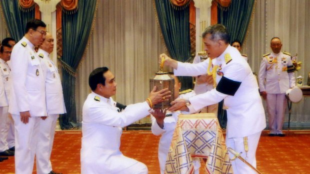 Thai King Maha Vajiralongkorn, right, passes the royal fire to Prime Minister Prayuth Chan-ocha to be used in ceremonies during the royal funeral and cremation of his father King Bhumibol last year.