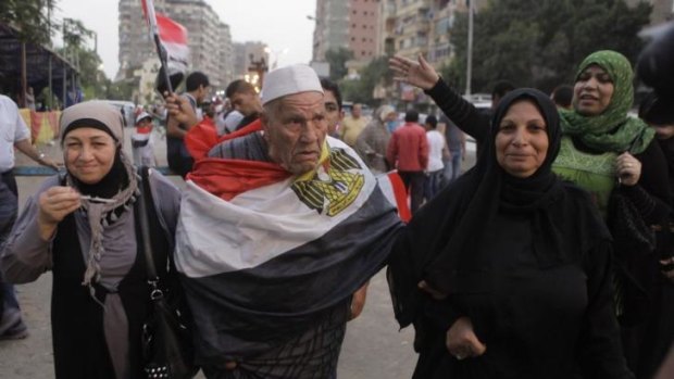 An elderly Egyptian voter covers himself with a national flag as he walks with his family outside a polling centre in Cairo during the second day of voting in the presidential election.
