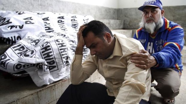A Pakistani volunteer comforts a man whose wife was killed by militants in Karachi after two teams of polio workers were attacked.