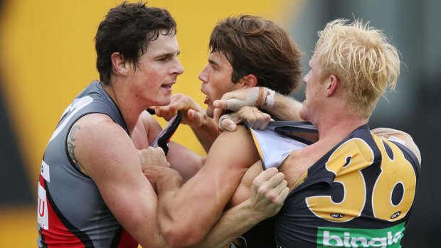 Jaker Carlisle (left) fights with Alex Rance and Steven Morris of the Tigers.