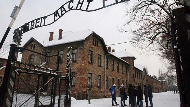 Tourists pause near the main entrance, with a replica of the inscription "Arbeit Macht Frei" ( translated to "Work Sets You Free") over the entranceway to the former Nazi death camp Auschwitz Birkenau.