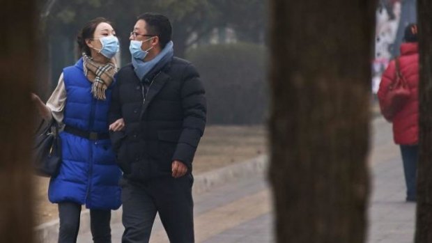 A couple wearing face masks walk along a street on a hazy afternoon in Beijing on February 24.