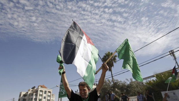 Nael Barghouti waves a green Islamic flag and a Palestinian flag to the crowd after arriving in Ramallah.