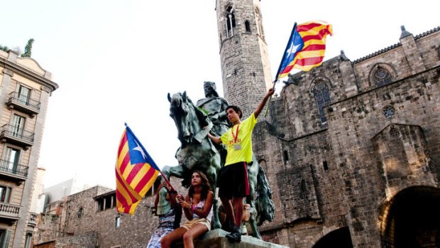 Protesters wave Catalan flags from the Ramon Berenguer III monument during a pro-independence march