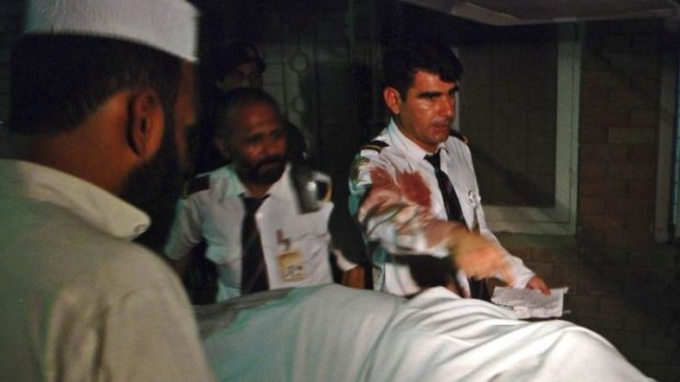 Plane attack: Crew members of a Pakistan International Airlines plane are seen beside the body of a woman who was killed on board their aircraft, at a hospital in Peshawar.