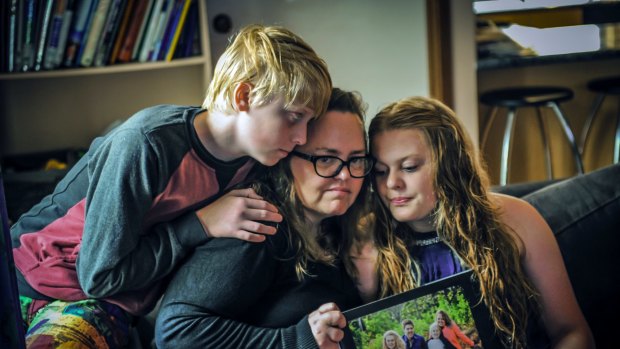 Stuart Heddle's wife Jenny, son Aidan,12 and daughter Jordan, 15 with a photo of their family in happier times.