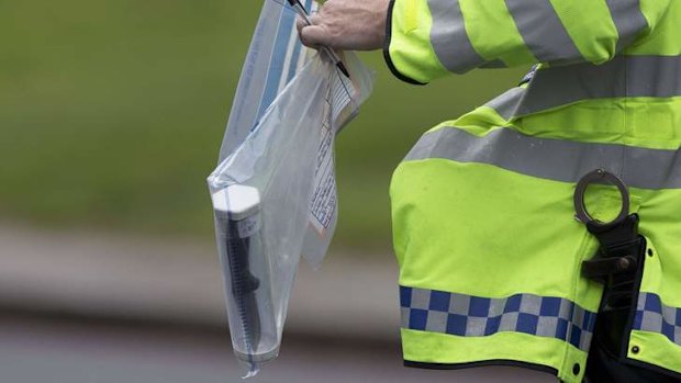 A police officer carries an evidence bag containing a knife.