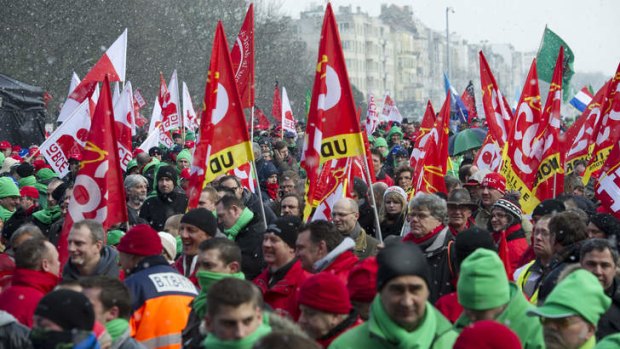 Union members wave flags and march during a demonstration outside of an EU summit in Brussels on Thursday, March 14, 2013. Germany leaders fear a revolution in Europe if youth unemployment isn't addressed.