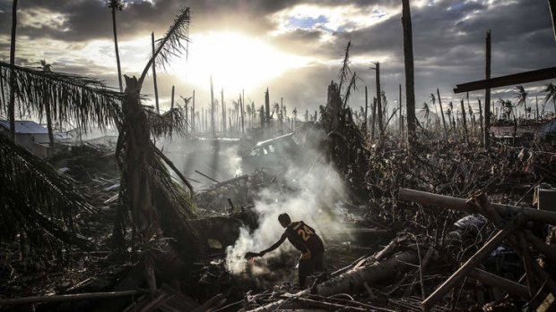 Life in ruins: A man fans a fire in Leyte, Philippines. About 600,000 people are yet to receive help, the World Food Program says.