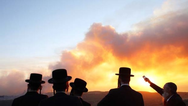 "Unprecedented" ... ultra-Orthodox Jewish men look on as the fire spreads across the north of Israel.