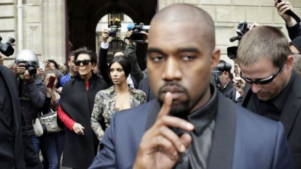 The secret might be out ... Kanye West walks ahead of Kim Kardashian (centre) as they leave their hotel in Paris.