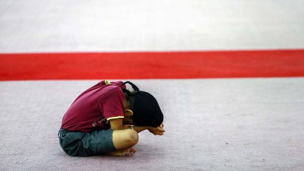 A child prays for passengers onboard the missing Malaysia Airlines Flight MH370.