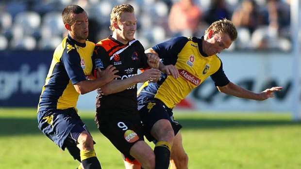 Closing in: Stefan Nijland of Brisbane Roar is caught between John Hutchinson and Daniel McBreen of the Mariners at the weekend.