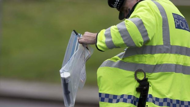 Grisly find: A police officer carries an evidence bag containing a knife near the scene of the killing.