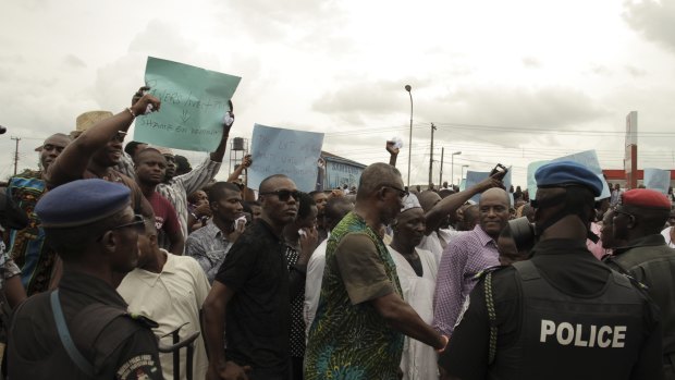 Security forces stand in front of protesters against the recent election in Nigeria's Port Harcourt on Sunday.