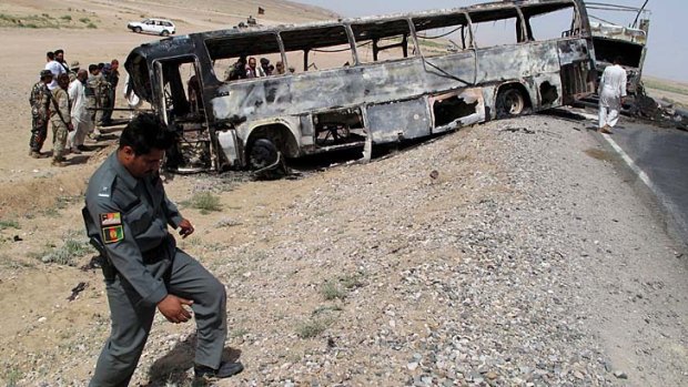 Traffic police officials inspect the remains of a passenger bus which collided with a fuel tanker truck in Kandahar province.