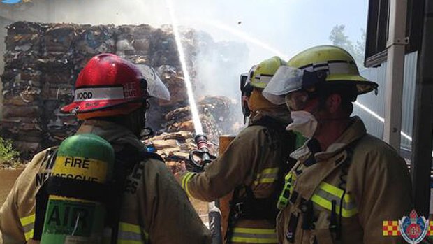 Firefighters hose down a pile of paper at a mill in Matraville.
