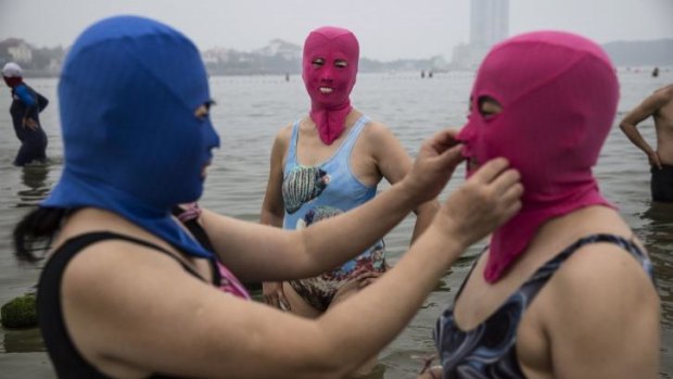 Let me fix that ...  A Chinese woman adjusts another's facekini before going for a swim.
