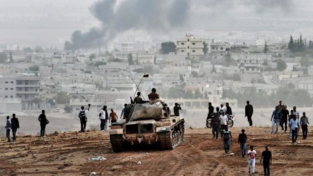 Spectators: Turkish soldiers and Kurdish people observe Kobane's unfolding tragedy.