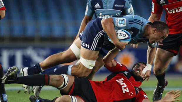 Chris Lowrey of the Blues drives over the top of Sam Whitelock of the Crusaders.