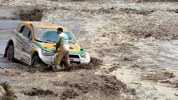 Rally chaos ... Brazil's Youssef Haddad stands next to his Mitsubishi stuck in a river.