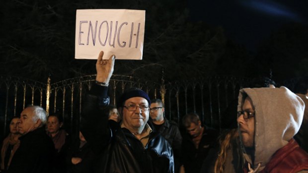 A protester raises a placard during an anti-bailout rally outside the presidential palace in Nicosia, Cyprus.